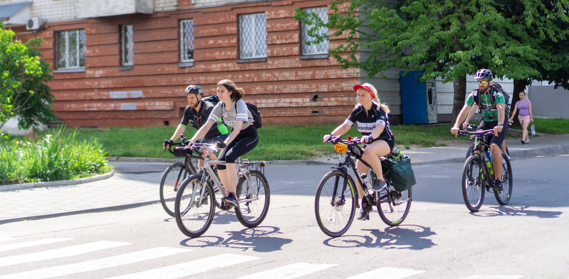 Двоє жінок та двоє чоловіків на велосипедах рухається в одному напрямі